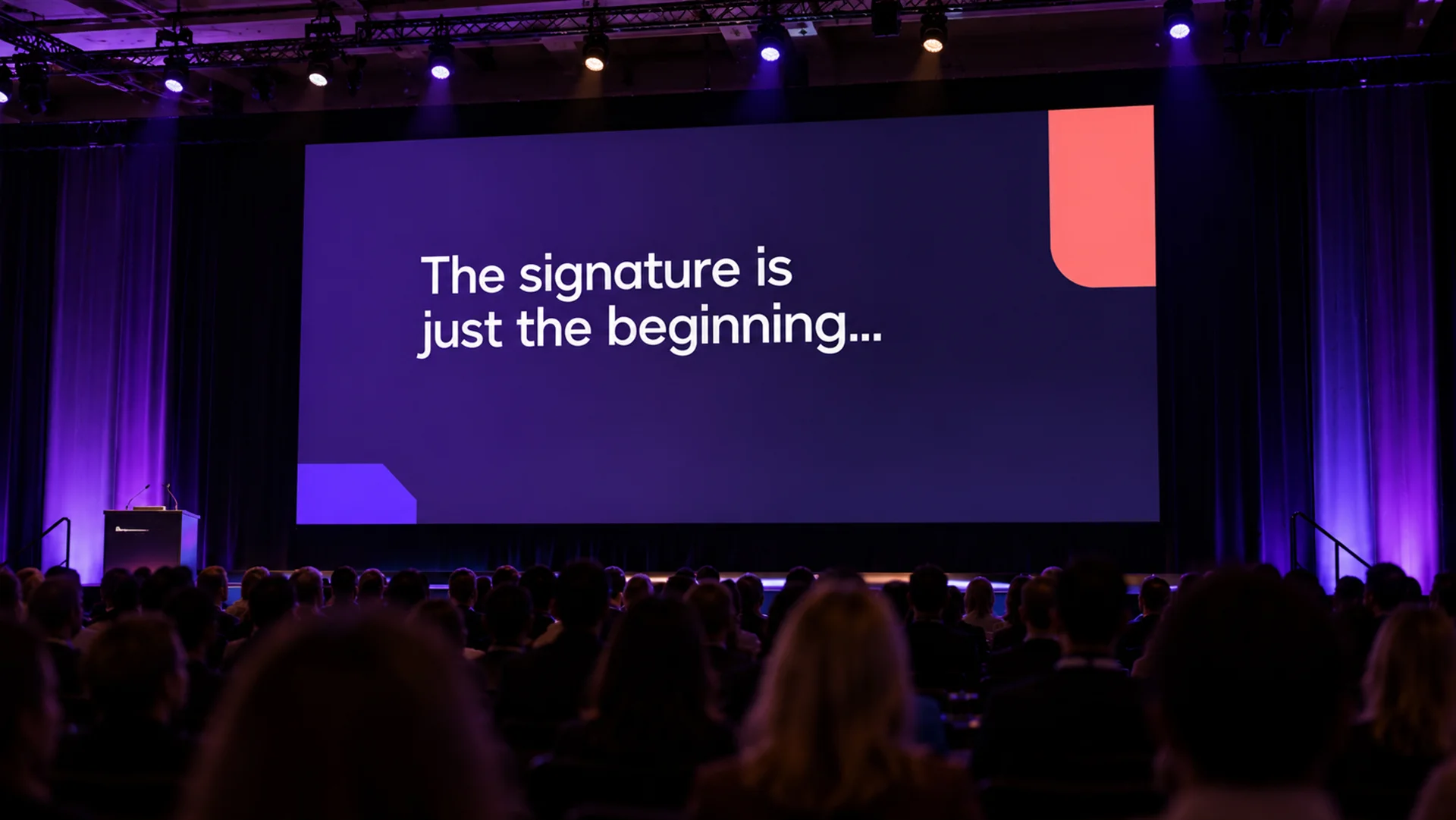 On a conference stage, a large screen reads &ldquo;The signature is just the beginning&hellip;&rdquo; above a darkened audience.