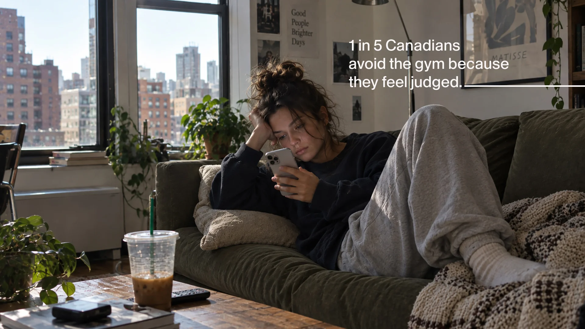 A woman in sweats lies on a couch scrolling her phone, beside the line &ldquo;1 in 5 Canadians avoid the gym because they feel judged.&rdquo;