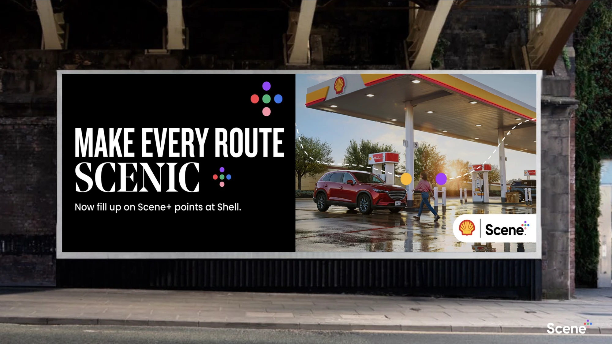 A street billboard reads &ldquo;Make every route scenic. Now fill up on Scene+ points at Shell&rdquo; beside a photo of a woman walking past a red SUV at a Shell station.