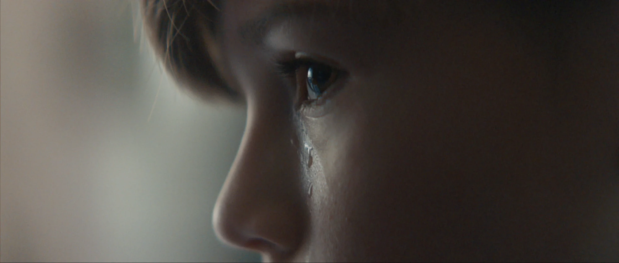 Close-up of a boy&rsquo;s face in profile, a tear running down his cheek.